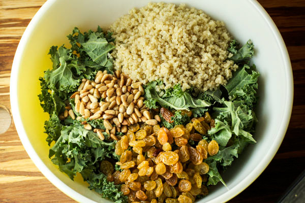 A white bowl filled with the ingredients for Kale Quinoa Salad before mixing together.