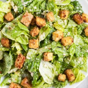 An overhead shot of a plate of vegan caesar salad with sesame-tofu croutons on top