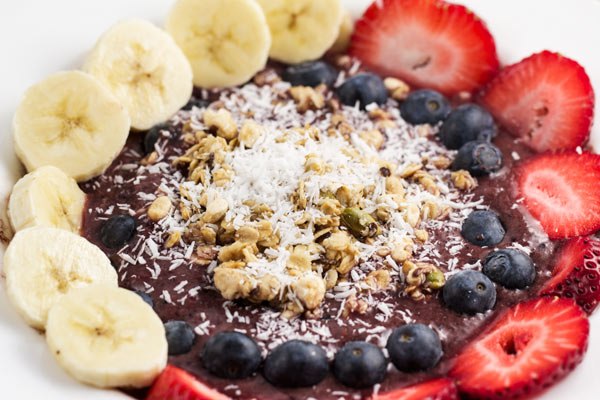 A closeup of an acai bowl with bananas, strawberries and other toppings.