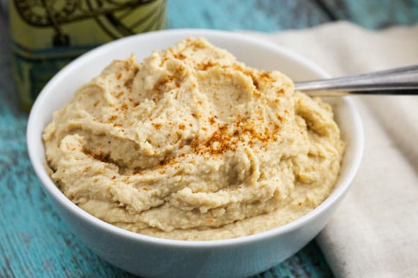 A white bowl filled with roasted garlic hummus.