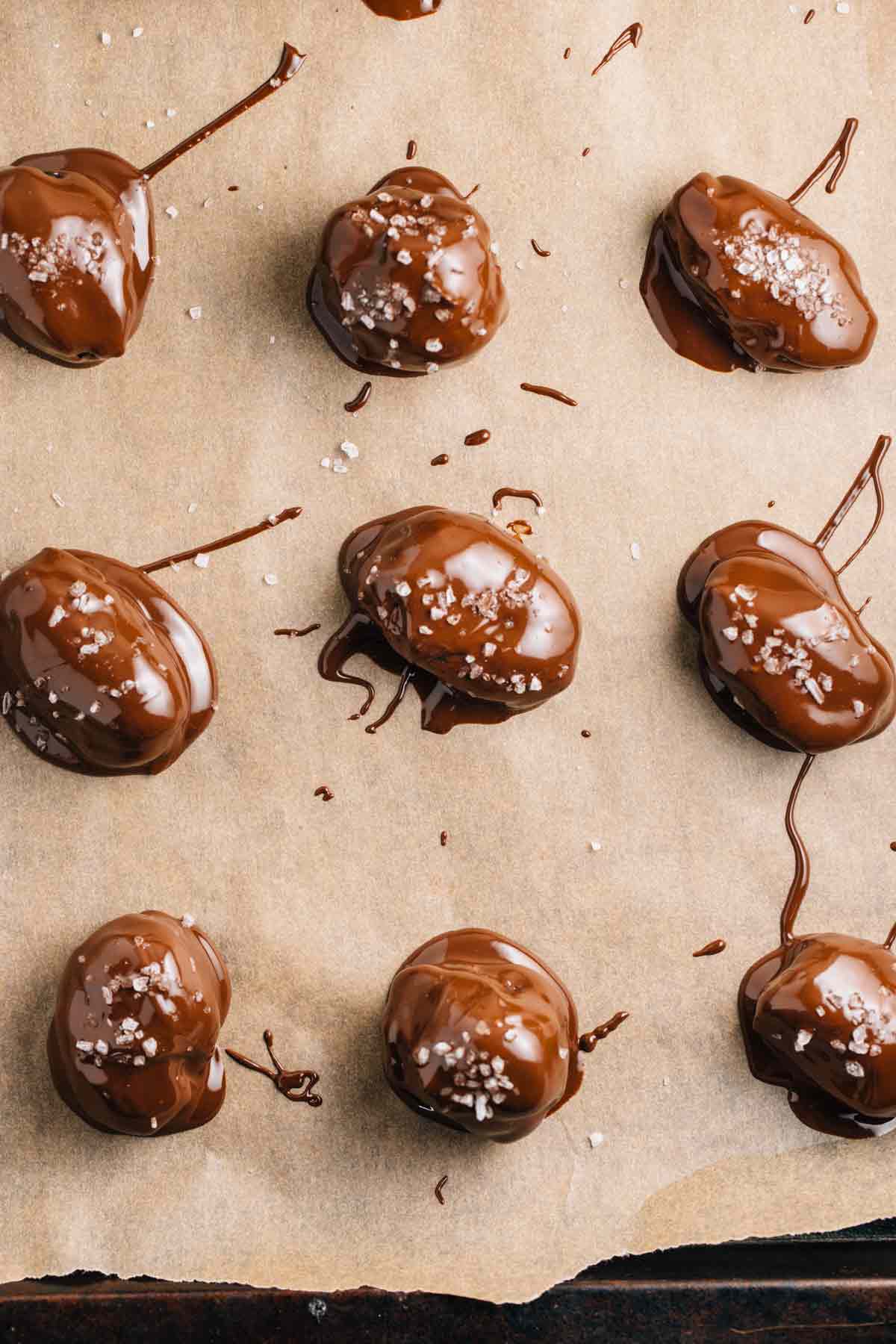 A baking sheet with parchment paper covered with chocolate covered dates.