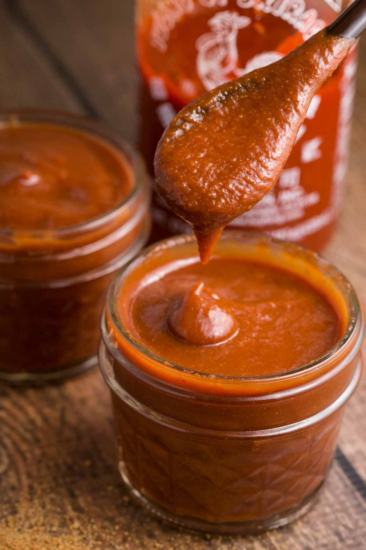 Vegan Barbecue sauce in a small mason jar dripping from a spoon.