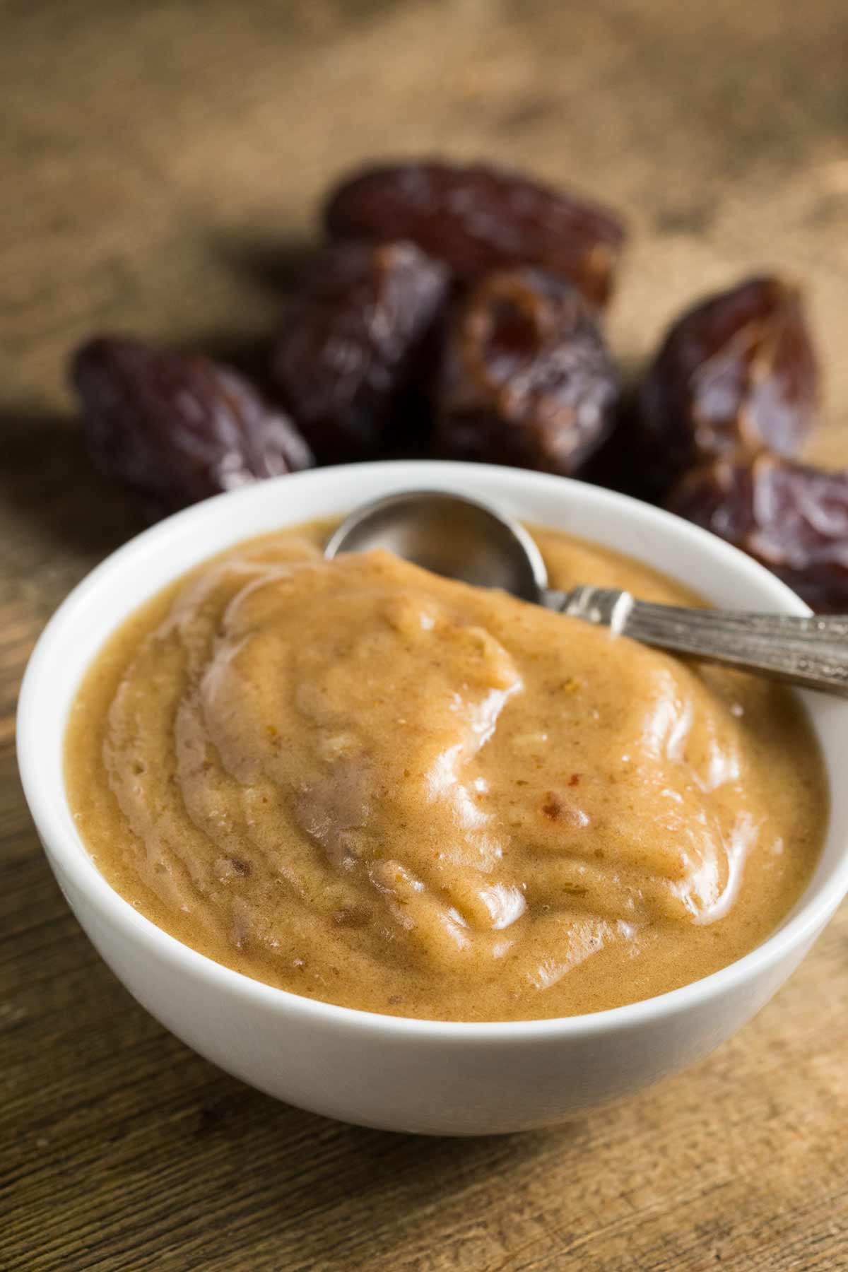 Date paste in a white bowl with a spoon.