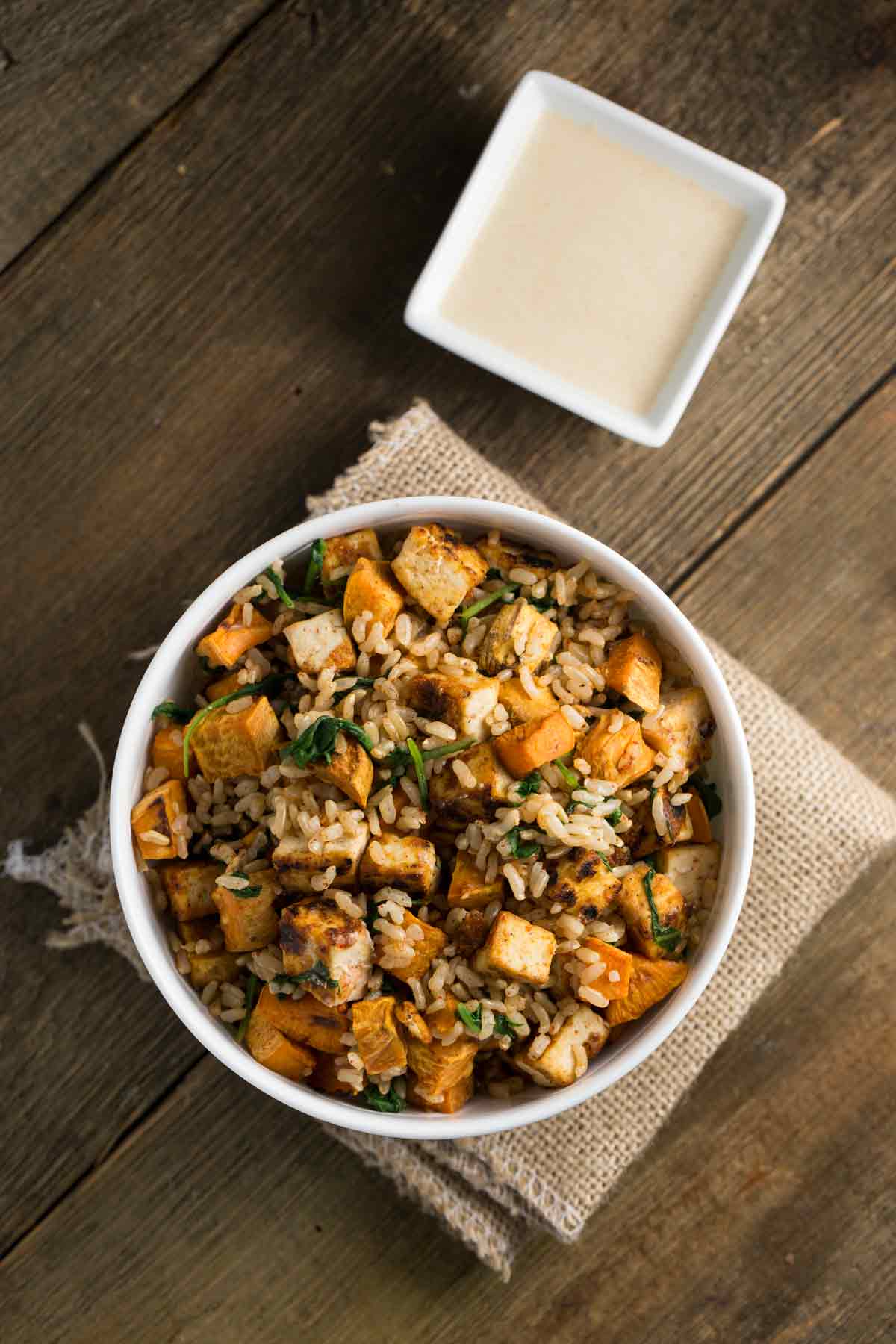 Overhead view of a bowl of tofu sweet potato rice bowl with greens.