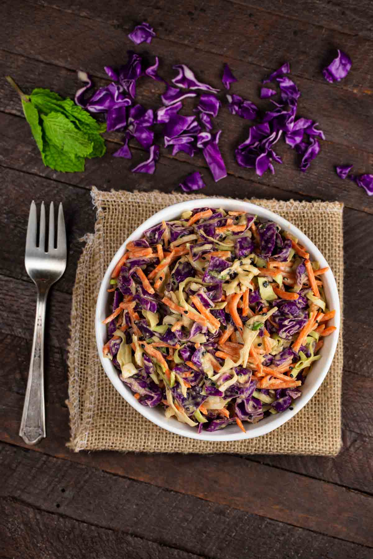 An overhead shot of a bowl of miso peanut coleslaw with a fork on the side