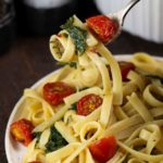 Spinach and Fennel Fettuccine with Roasted Tomatoes, with a fork holding a bite of pasta.