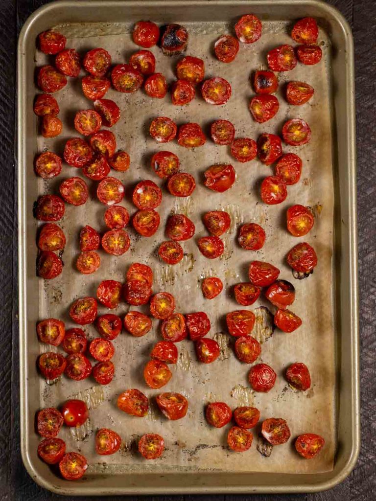 A baking sheet covered in parchment paper and halved cherry tomatoes, broiled until just starting to brown. 
