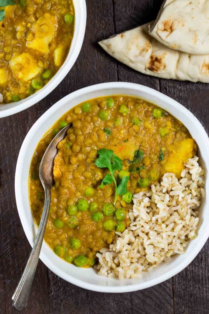 Indian lentil keema with peas and potatoes, in a white bowl with naan bread.