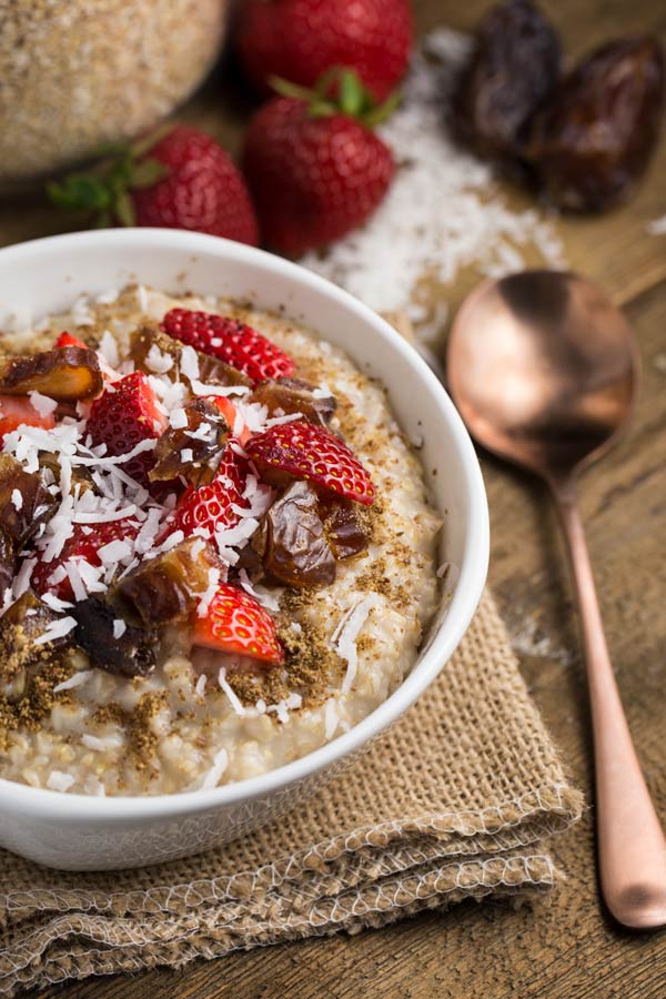 A bowl of steel cut oatmeal topped with coconut, brown sugar and strawberries.
