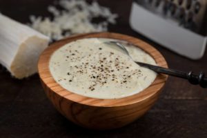 A wooden bowl filled with horseradish sauce and a small spoon