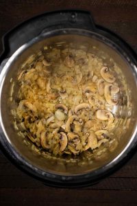 An overhead shot of an Instant Pot, sautéing onions and mushrooms.