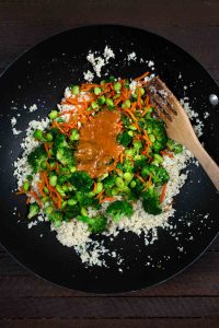 Cauliflower, veggies and sauce in a wok