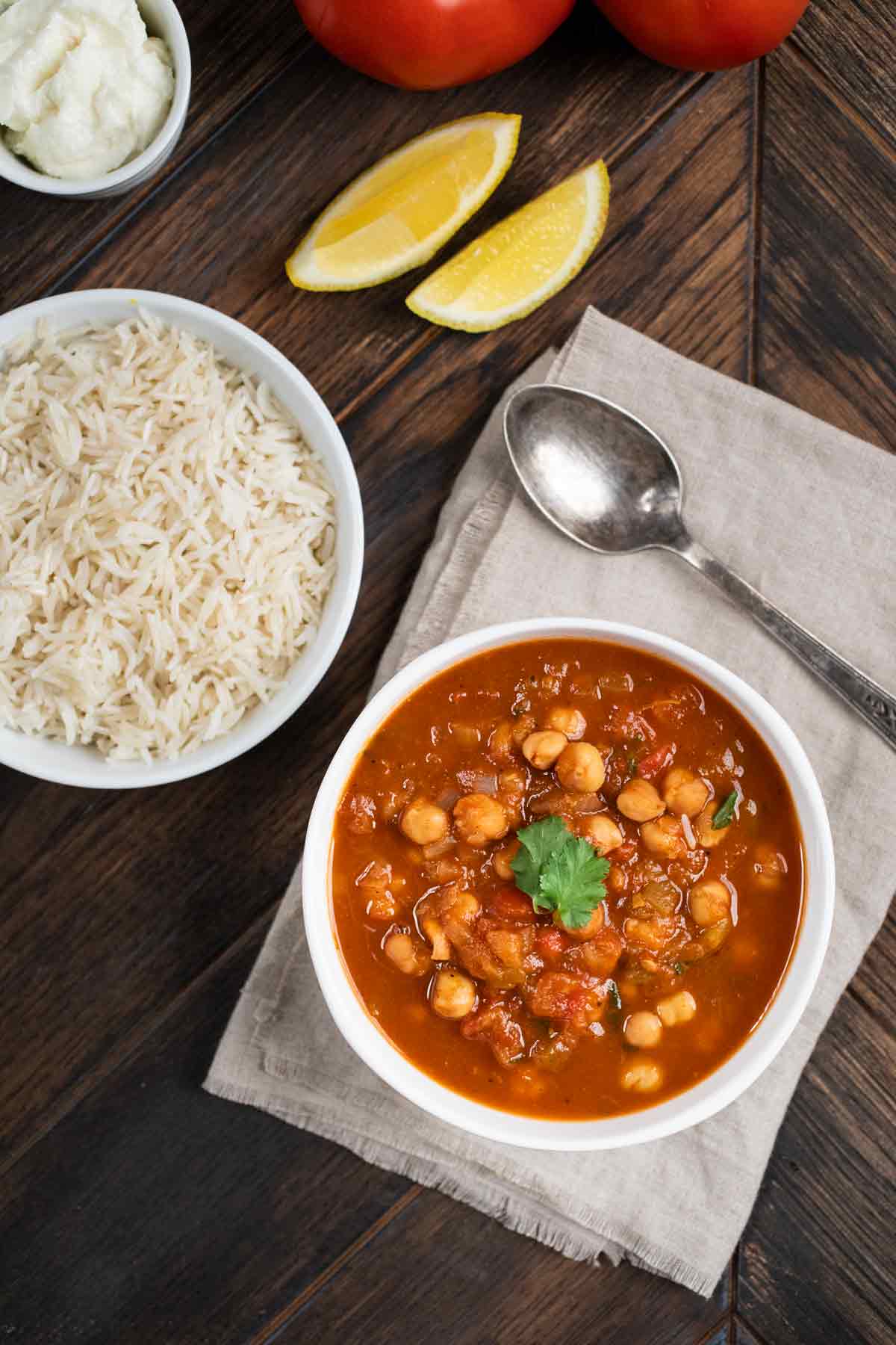 An overhead shot of a bowl of Instant Pot Chana Masala with a side of rice and garlic sauce. 
