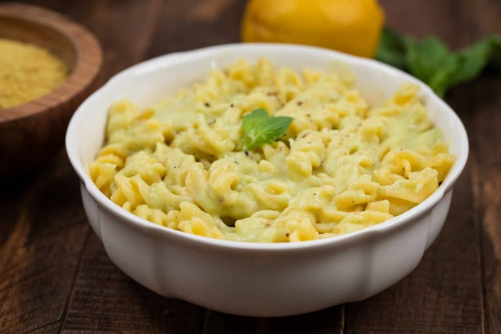 A white bowl filled with creamy cauliflower pasta with fresh basil.