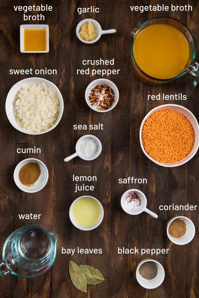 An overhead shot of all of the ingredients for crushed lentil soup, such as lentils, water, vegetable broth, onion and spices.