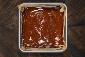 An 8x8 pan with a peanut butter mixture covered with melted chocolate.