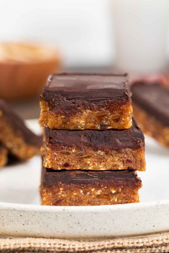 2 no bake vegan peanut butter chocolate bars stacked on a plate.