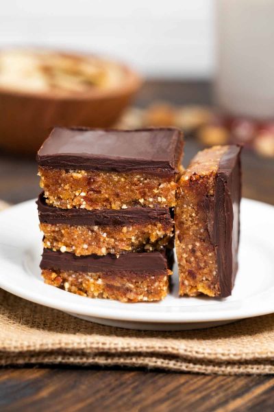 A plate of no bake vegan peanut butter chocolate bars, stacked on each other.